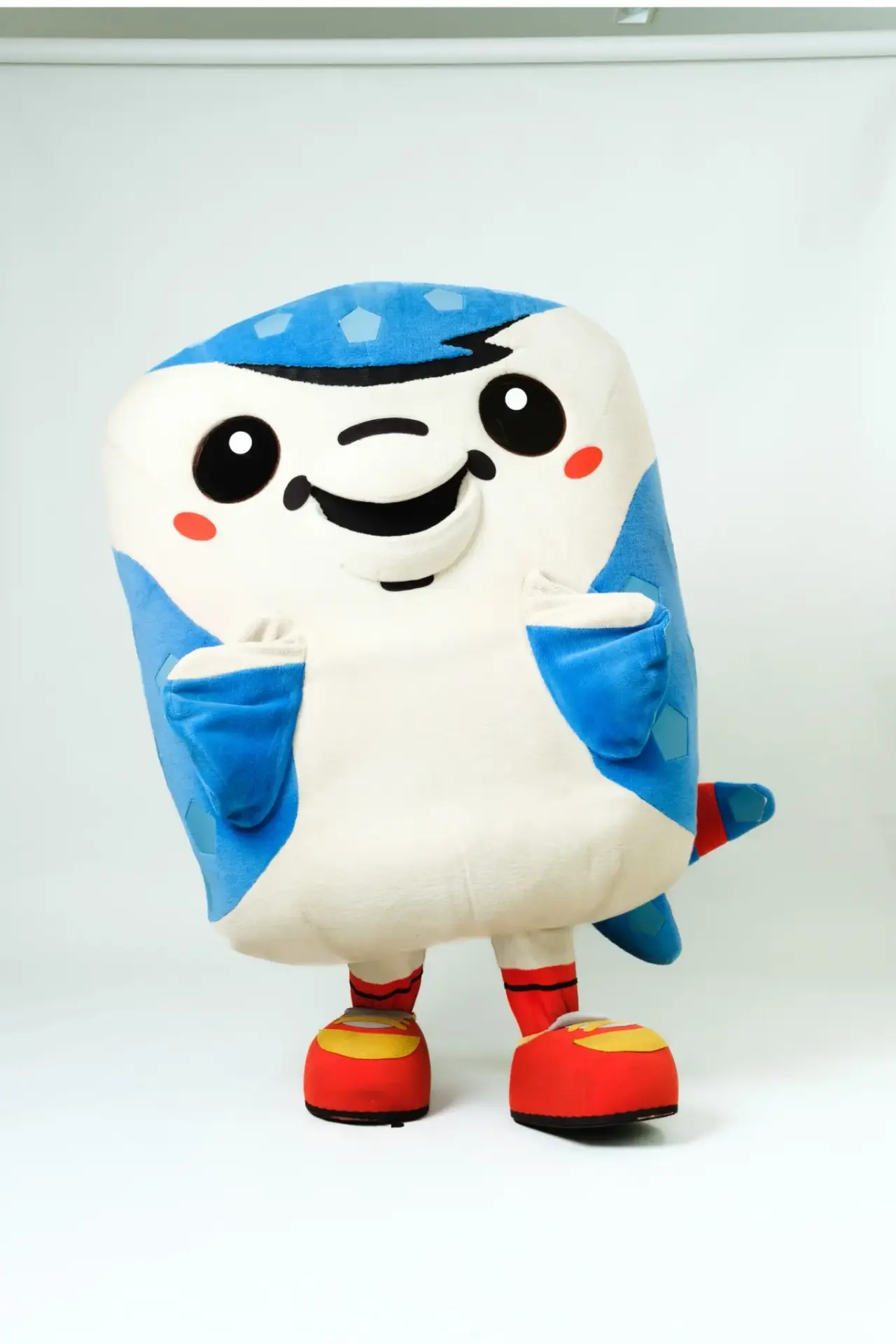 La mascota de peluche de Jinnbenyo, un pez sonriente y colorido.
