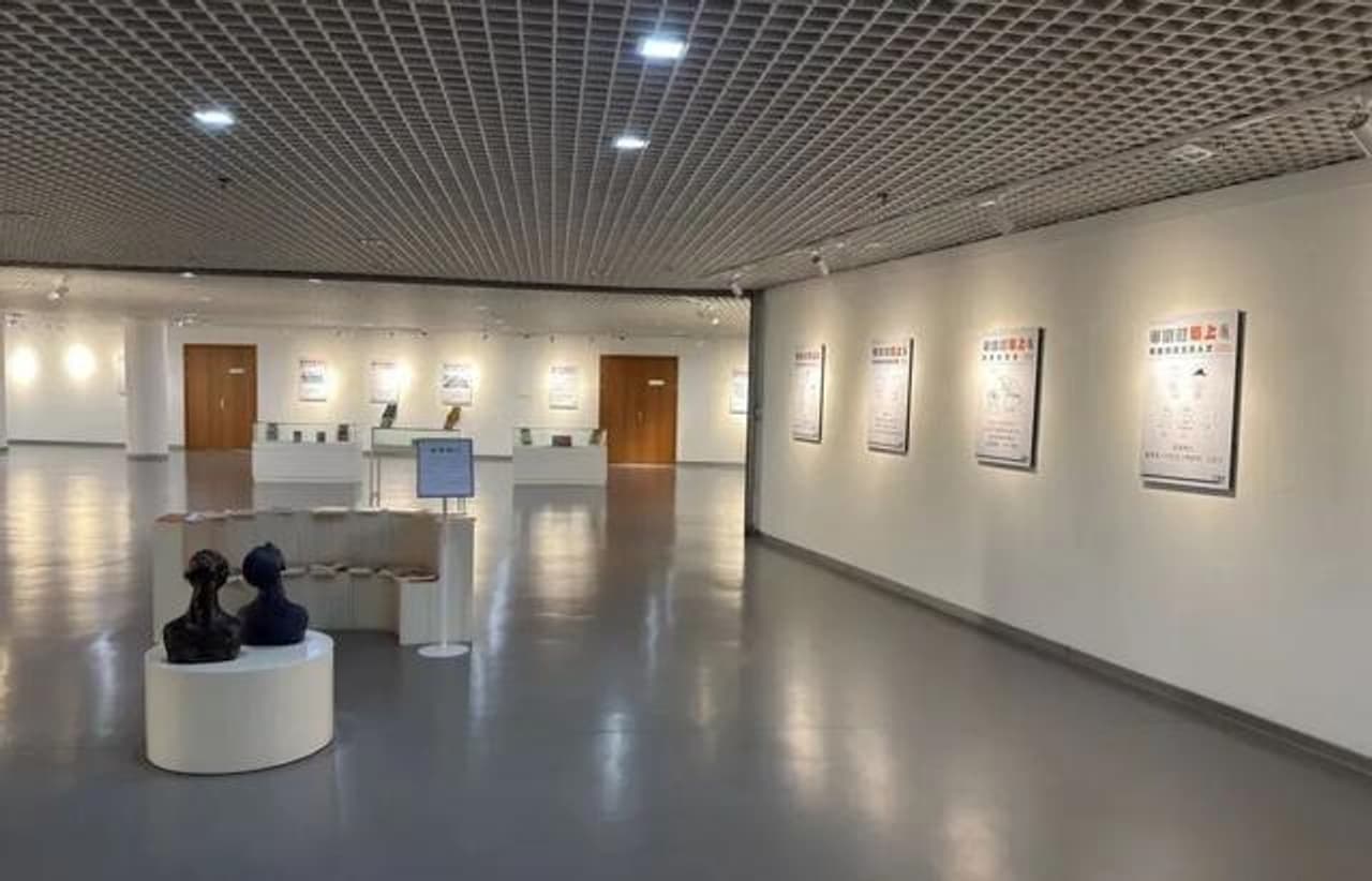Sala de la exposición con obras en las paredes y esculturas en el centro.