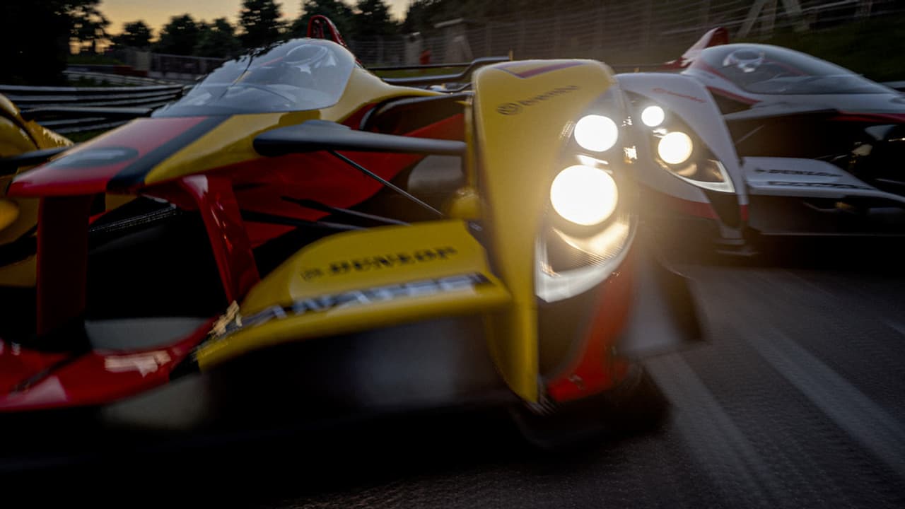 Dos coches de carreras en una pista durante el atardecer.