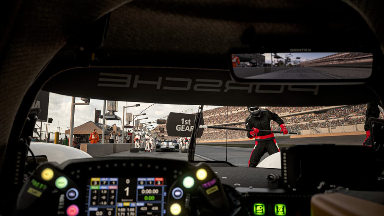 El interior de un coche de carreras con un equipo de pit stop al fondo.