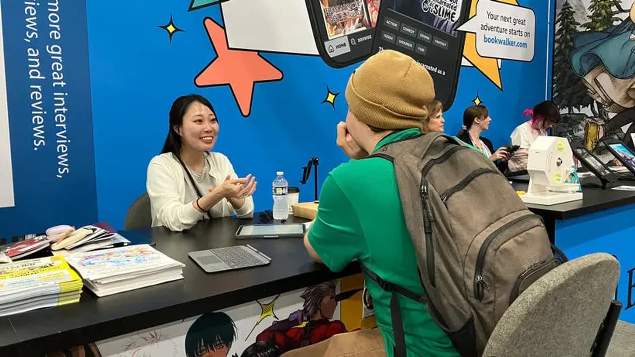 Una editora conversa con un visitante en el stand de KADOKAWA.