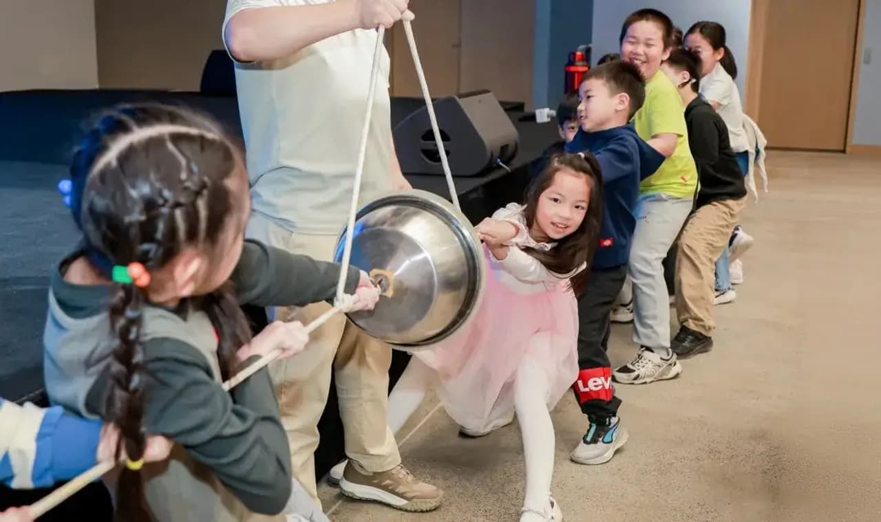 Un grupo de niños participa en una actividad de tirón de cuerda en un evento.